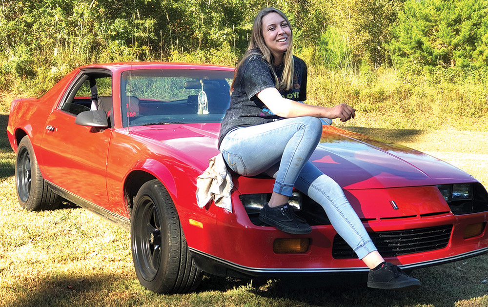 A smiling Briana Gaines sits atop her labor of love, a 1986 Chevrolet Camaro that the Roane State Community College student has been restoring for the past three years.