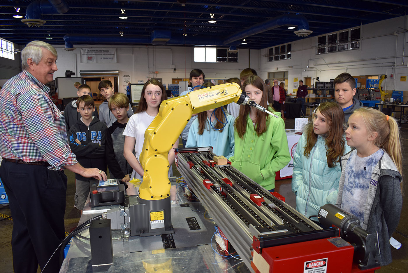 Gordon Williams, left, director of the mechatronics program for Roane State, operates a robotic arm for middle school students participating in the kickoff of the “Dream It. Do It.” competition.
