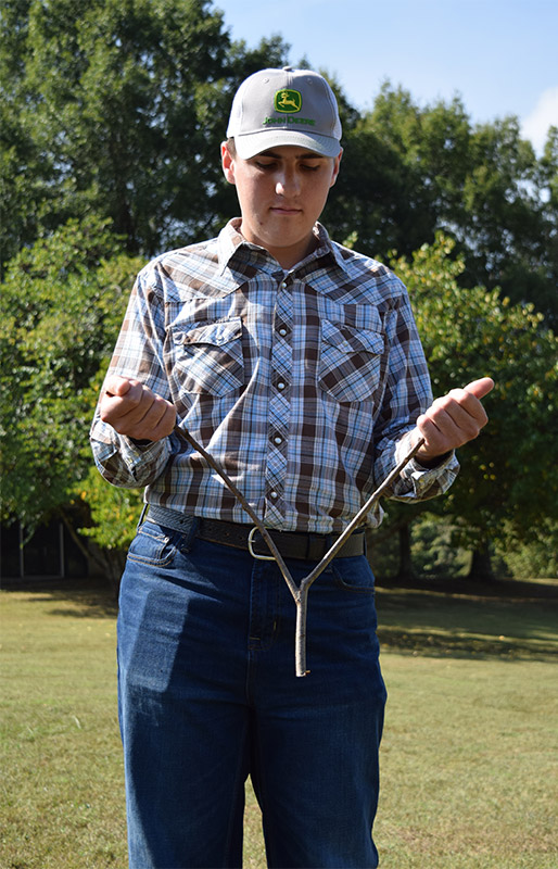Roane State student Clay Isham demonstrates the proper way to hold a dowsing rod to locate a subterranean source of water.