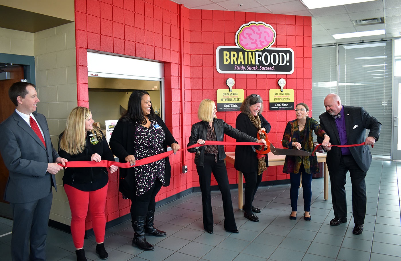 Sue Byrne, third from right, cuts the ribbon for the new “Brain Food” pantry, located in Roane State’s Coffey/McNally Building in Oak Ridge. She is the assistant project manager for the First Presbyterian Church of Oak Ridge’s partnership to help stock the campus’s pantry. From left: Scott Niermann, executive director of the Roane State Foundation; Kristie Hopwood, agency relations coordinator for Second Harvest Food Bank of East Tennessee; Kara Allen, an assistant manager of the Kroger Store in Oak Ridge; Melissa Eads, corporate affairs manager for the Kroger Nashville Division; Sue Byrne; Karen Brunner, vice president of Roane State Institutional Effectiveness and Research; and Roane State President Chris Whaley.
