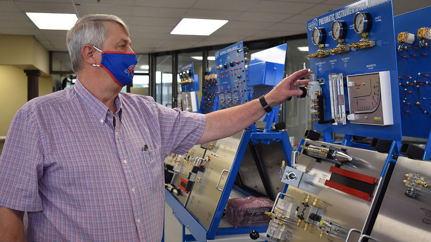 Wearing a Roane State-branded face mask, Gordon Williams, director of the community college’s mechatronics program, assembles a component of the new lab in part of the Learning Center on the Roane County campus.