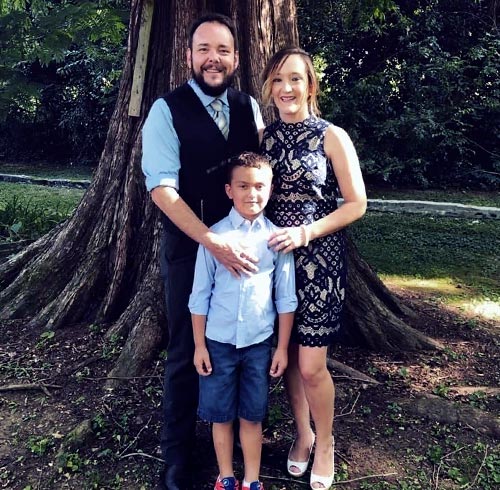 Dani Greenwell and family standing in front of a tree