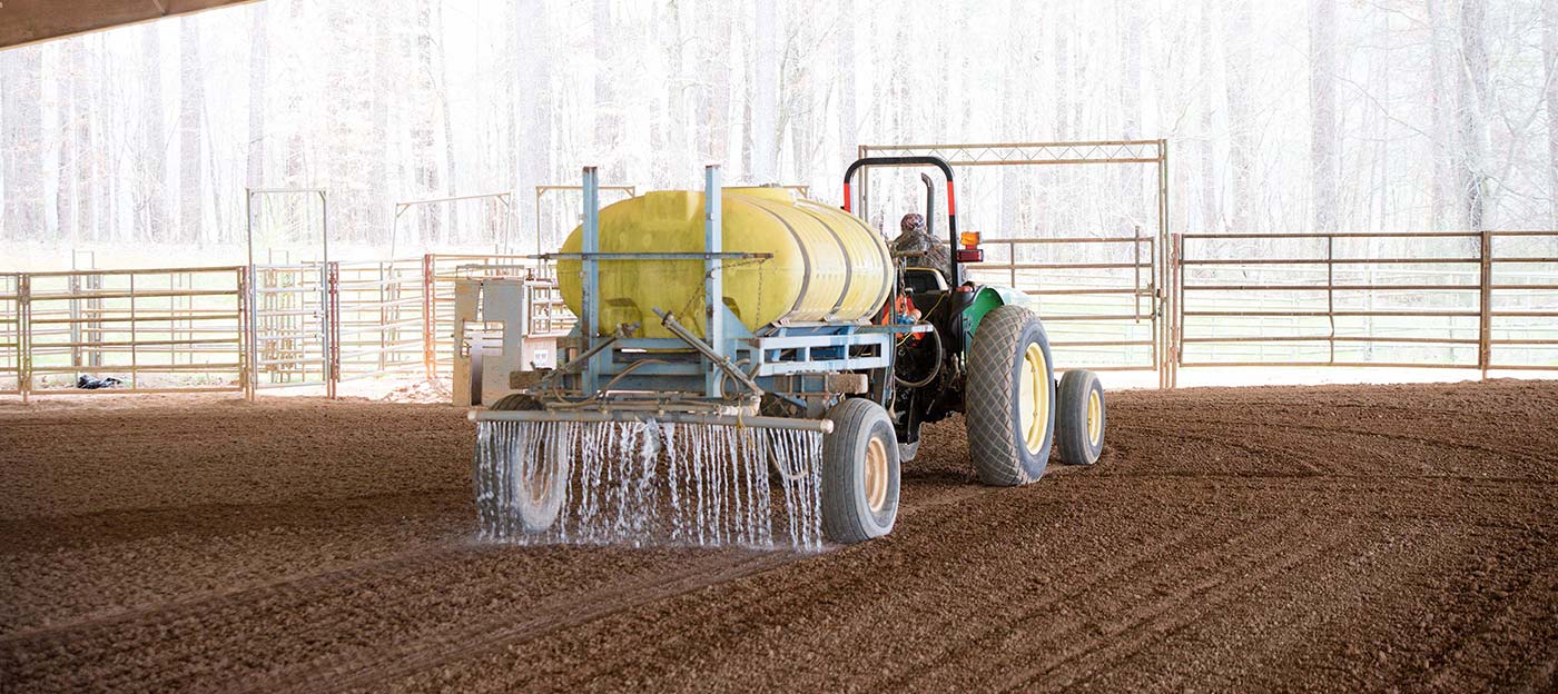 Tractor spreading liquid on dirt.