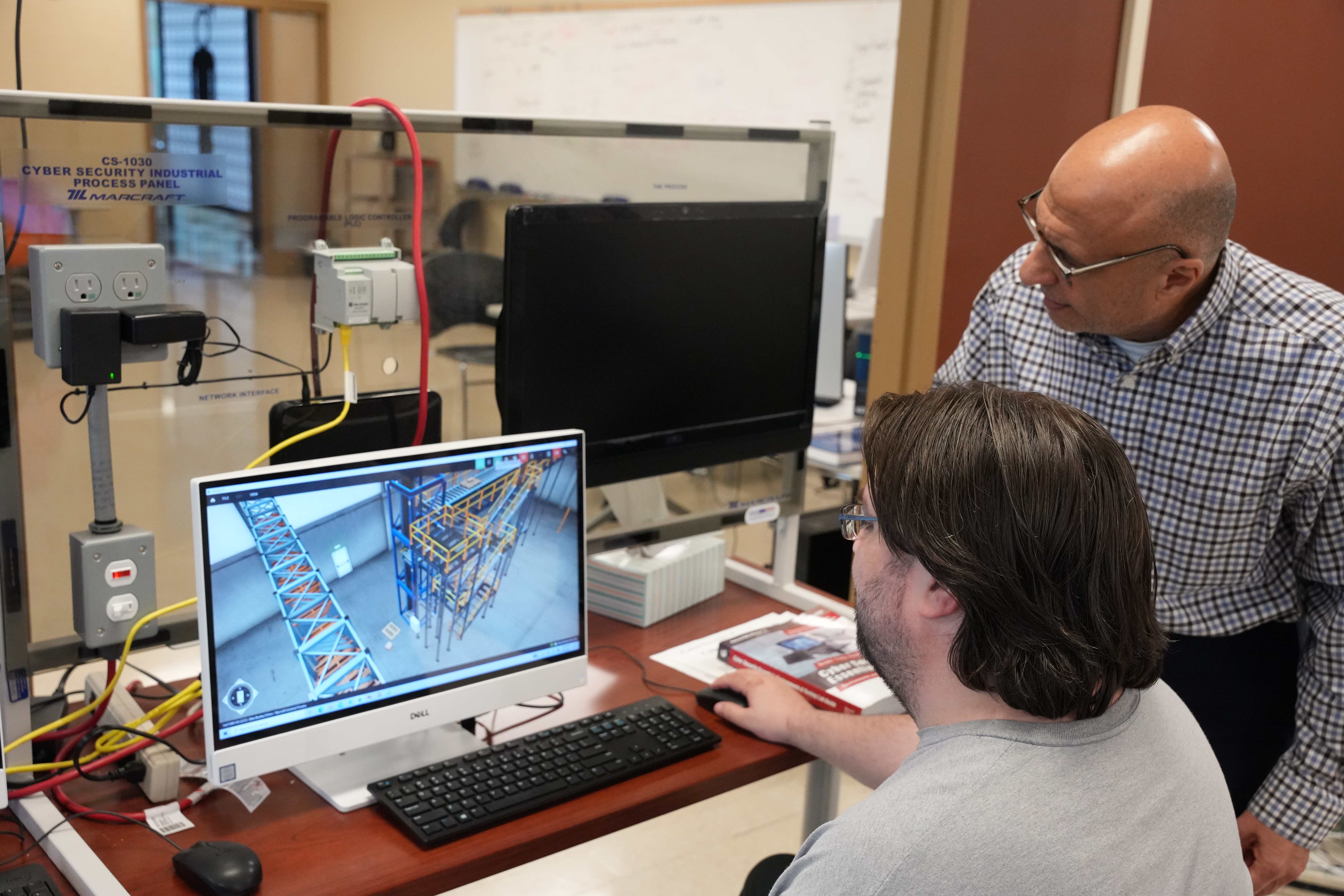 Student analyzing complex cybersecurity data on multiple monitors