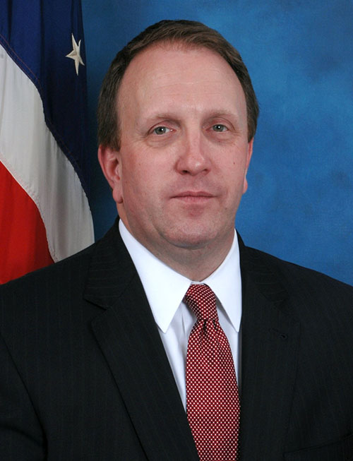 Jeff Peterson standing in front of a US flag