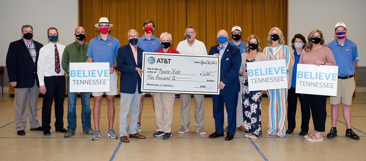 Group presenting a large check with signs that say Believe Tennessee