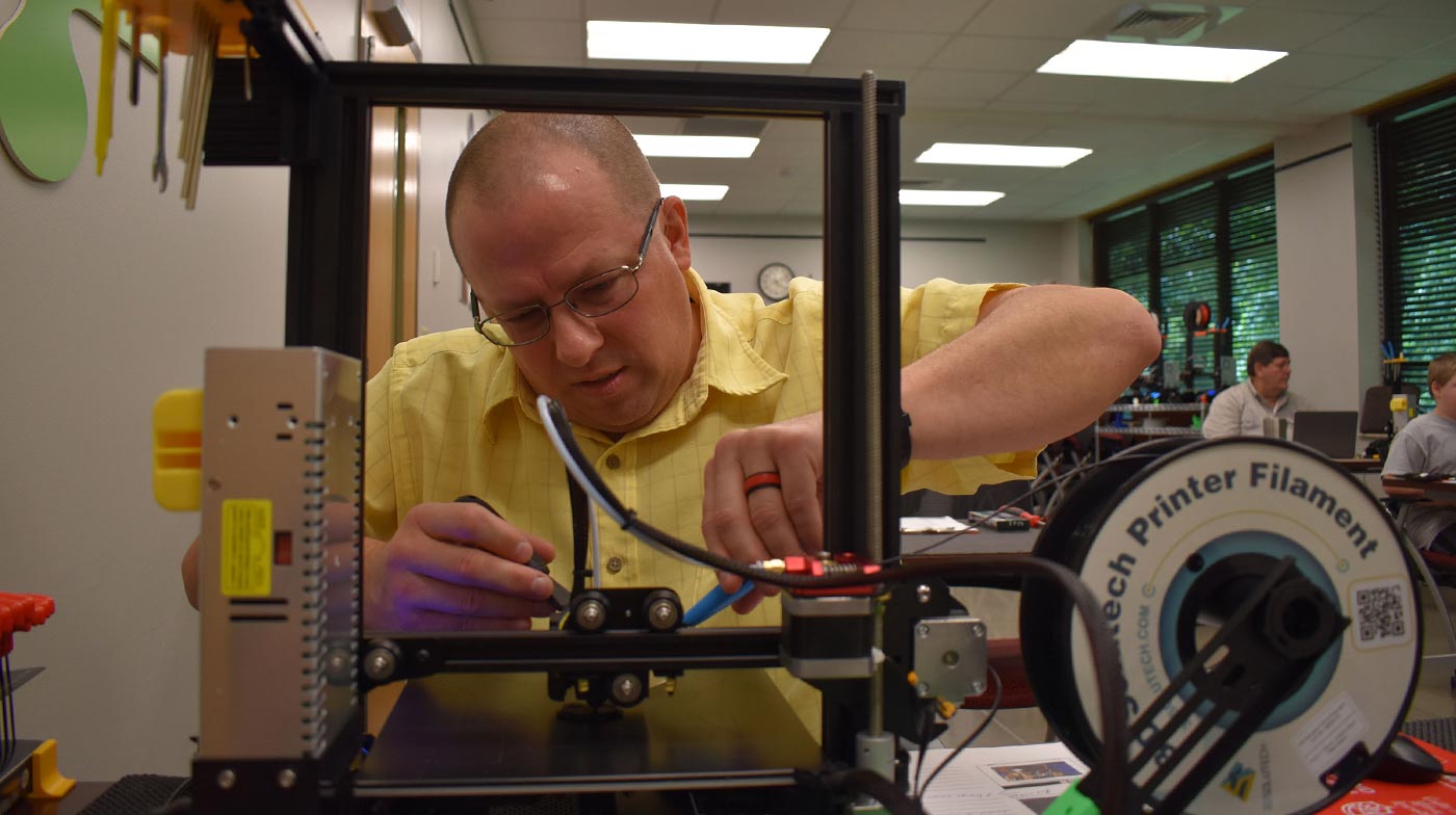 Cory Sanford puts the finishing touches on a 3D printer