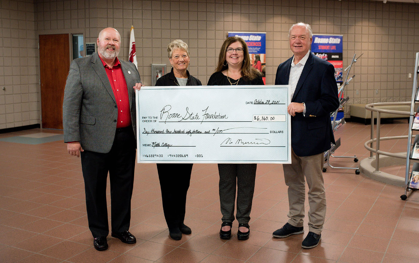 Four individuals holding a large check