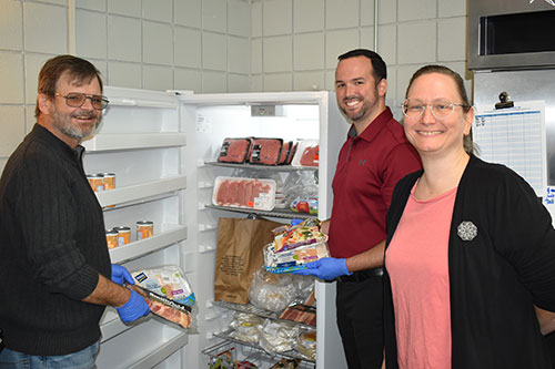 3 individuals standing in front of an open freezer