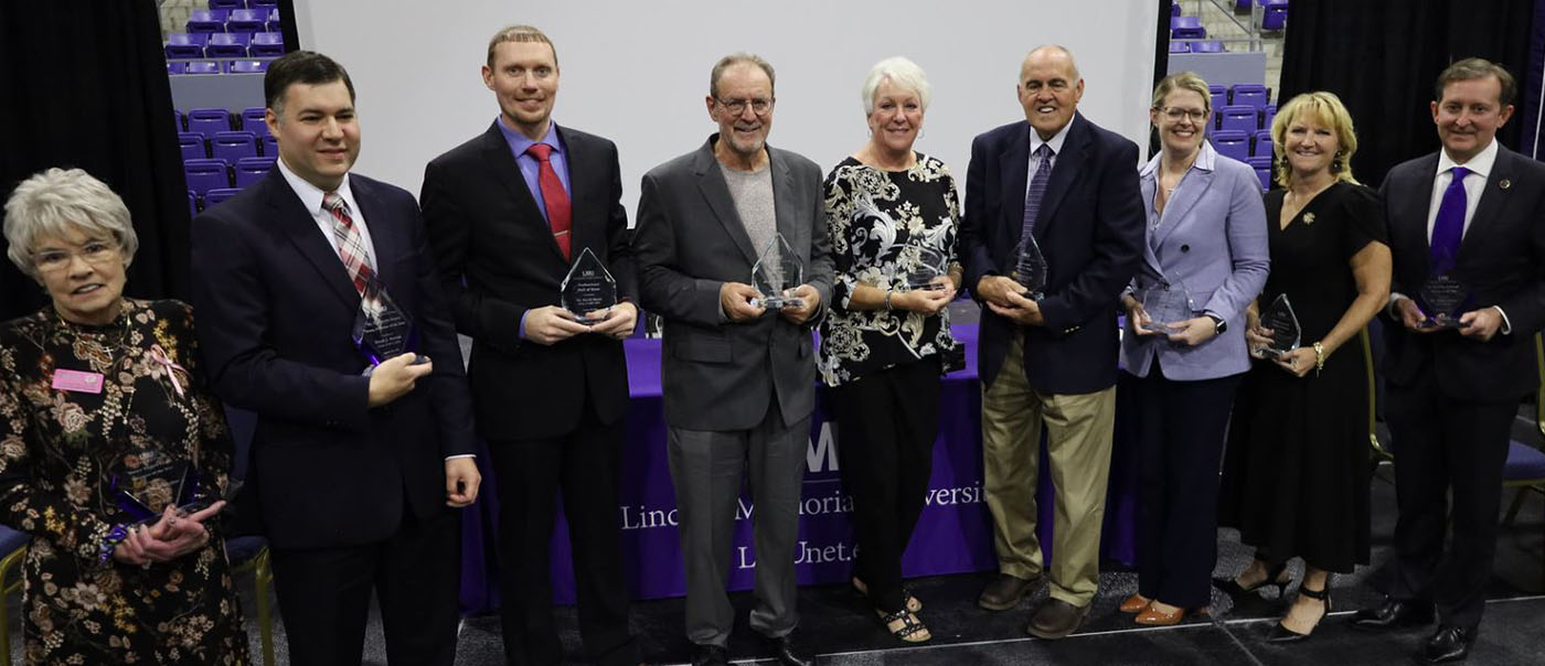 Group standing holding awards. Ralph Monday stands, fourth from left.