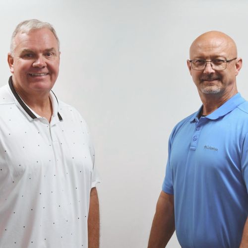 Two people standing in front of a white background.