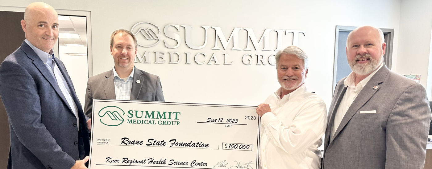 Four people holding a large check.