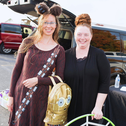 Two people in costume standing in front of vehicle.