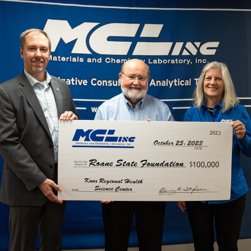 Three people holding a large check.