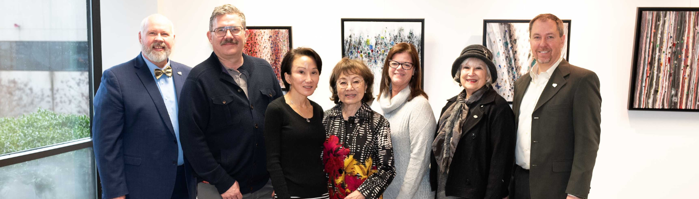 A group of people standing in front of paintings in an art gallery.