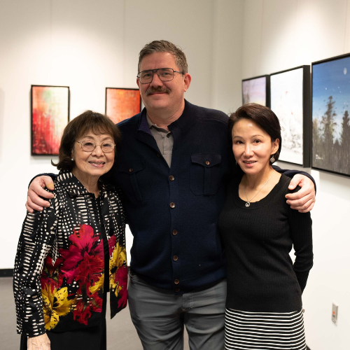Three people standing in an art gallery.