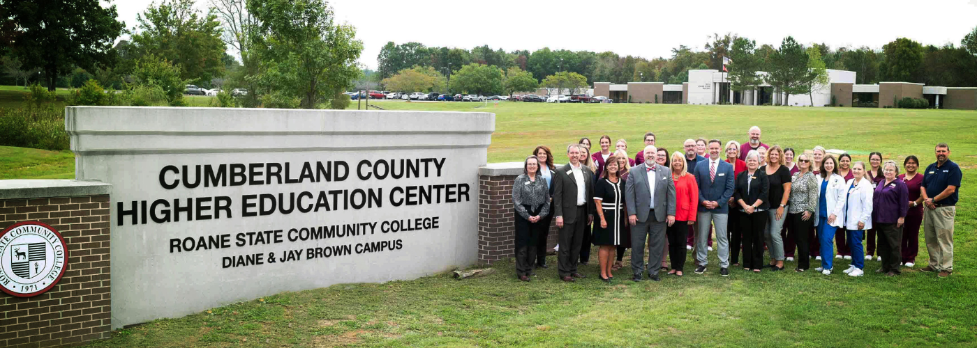 A group of people standing with a sign.