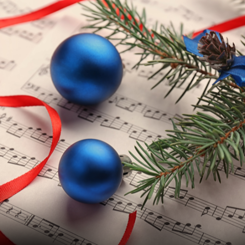 A piece of music with Christmas ornaments on top.