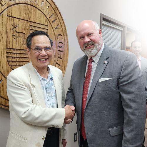 Two men shake hands in an office.