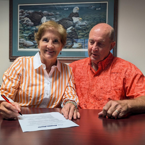 A couple sitting at a table and signing a document.