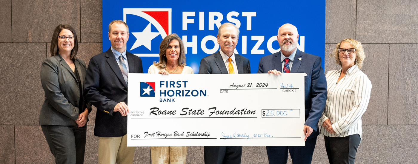 A group of people holding a large check at a bank.