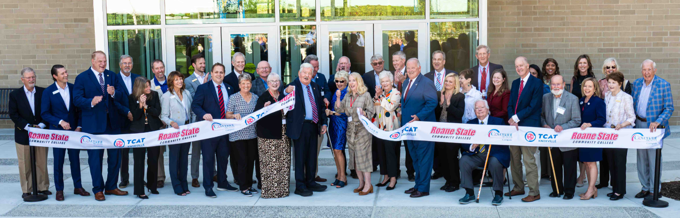 A group of people cutting a ribbon for a new college campus.