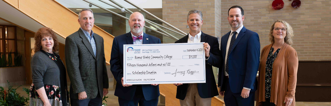 A group of people standing in a hospital lobby holding a large check for $15,000.
