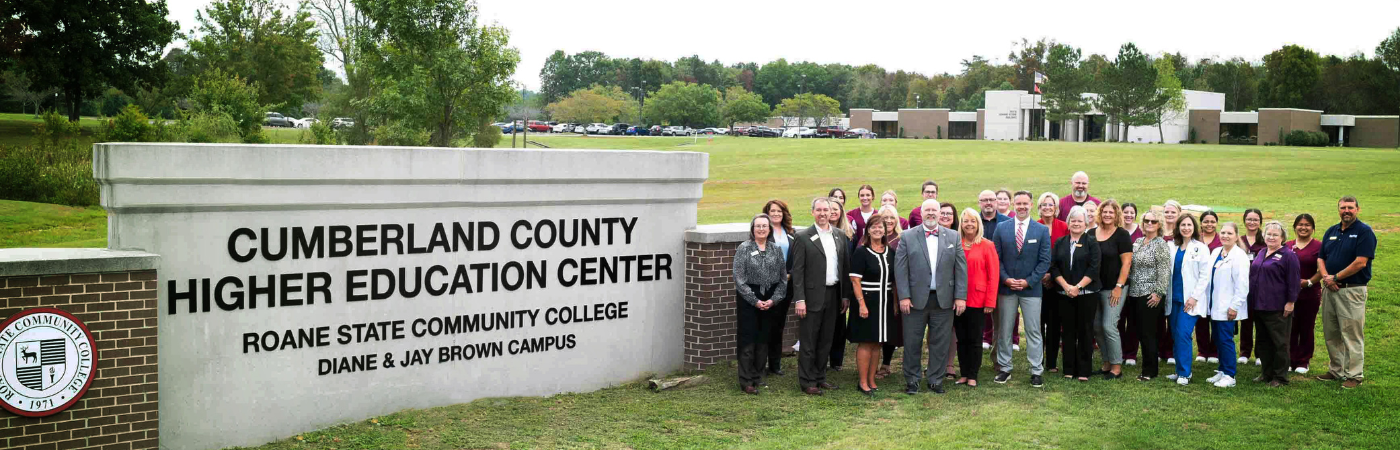 A group of people standing near the Cumberland County campus sign.