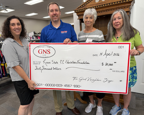 A group of people standing in a store holding a large check for $30,000 to Roane State Foundation.