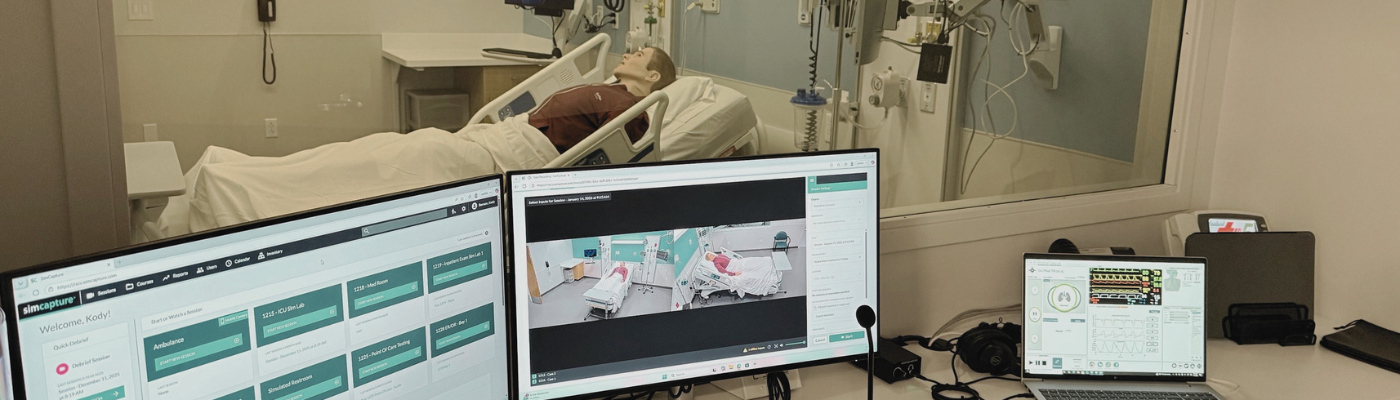 Computers showing healthcare simulation software with a patient manikin in the background.